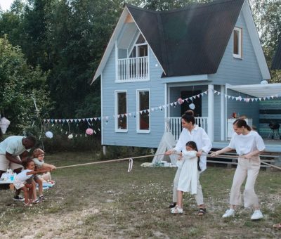 Happy family playing tug of war in front of cozy houses during a summer day.