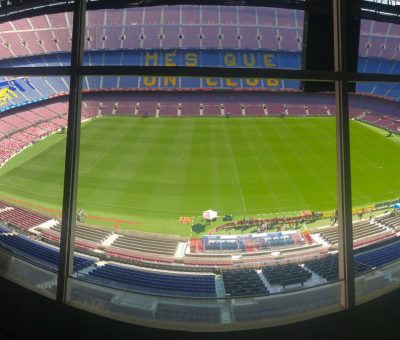 Wide view of Camp Nou stadium showcasing its vast seating and green pitch.