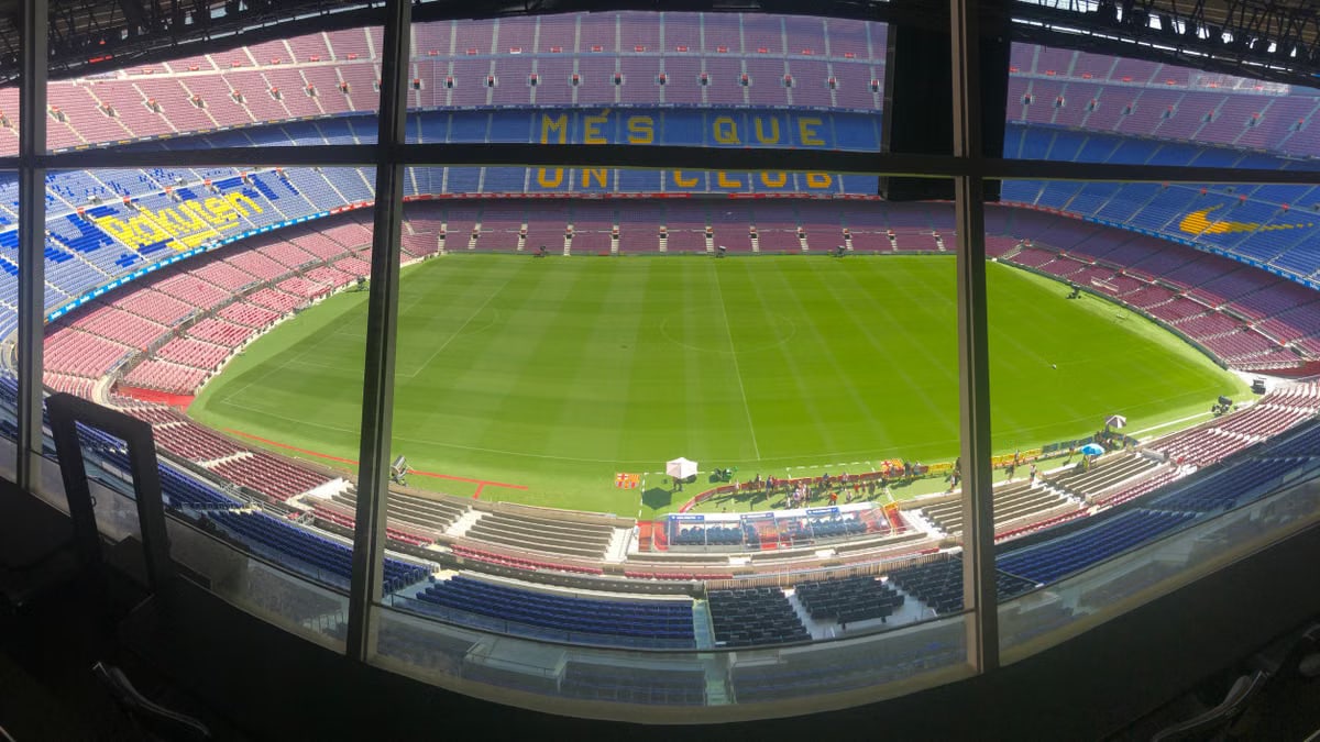 Wide view of Camp Nou stadium showcasing its vast seating and green pitch.